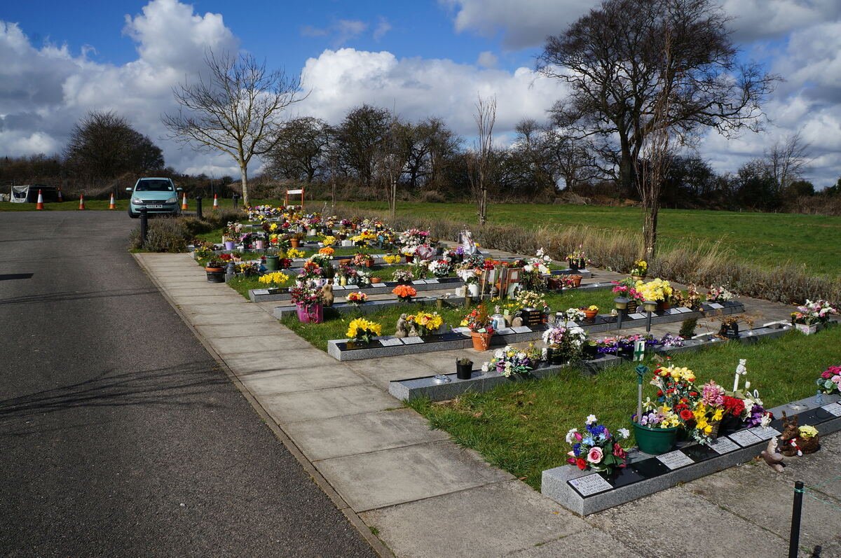 Rows of tidy headstones bright with seasonal flowers in a UK cemetery
